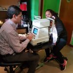 Con equipamiento oftalmológico se examina a una niña a upa de su madre